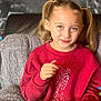 child, girl, pigtails, red_sweatshirt, leopard_print_leggings, popcorn, gummy_candies, bowl, blanket, couch, snacking, smiling, indoor, cozy, portrait, happy, casual_clothing, urban_background, seated, food