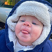 Bobby joined the competition — help win amazing prizes! baby, child, face, hood, jacket, coat, fleece, blue, white, tongue, outdoor, car, window, cold_weather, clothing, cute, infant, person, skin, expression