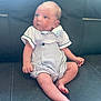 baby, infant, child, sitting, romper, striped_clothing, leather_couch, indoor, cute, small, skin, head, face, legs, feet, hand, curious, looking_away, person, young