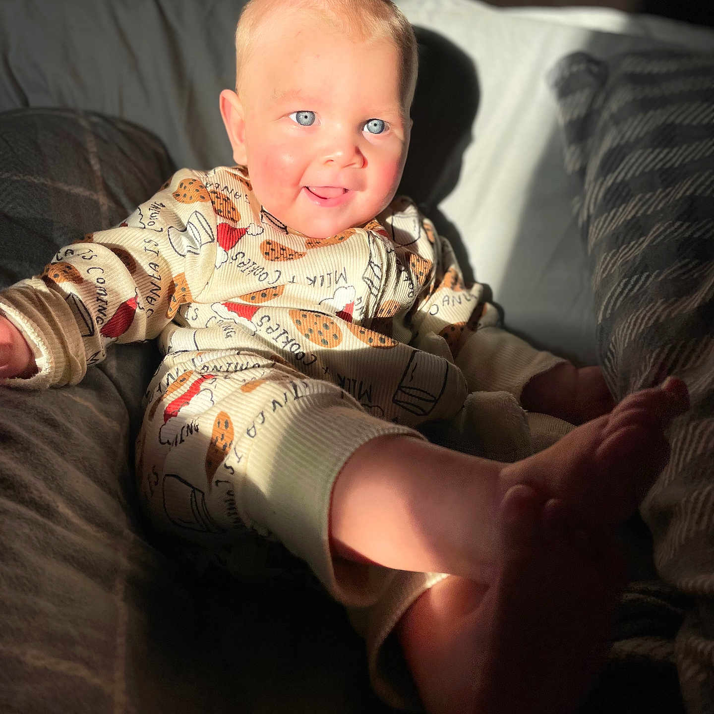 Bobby is registered to the contest to win money with this photo: baby, blanket, blue_eyes, child, clothing, couch, cozy, cute, face, feet, happy, home, indoor, infant, pajamas, person, portrait, relaxing, smiling, sunlight