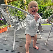 Bobby joined the competition — help win amazing prizes! baby, balancing, barefoot, chair, child, clothing, daylight, deck, furniture, greenery, happy, nature, outdoor, person, plants, portrait, smiling, sunny, toddler, wooden_floor