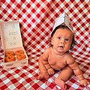 Sanova is registered to the contest to win money with this photo: baby, infant, donuts, krispy_kreme, paper_hat, red_and_white_checkered, blanket, food, box, celebration, half_birthday, cute, chubby, sitting, curly_hair, skin, expression, indoor, portrait, milestone