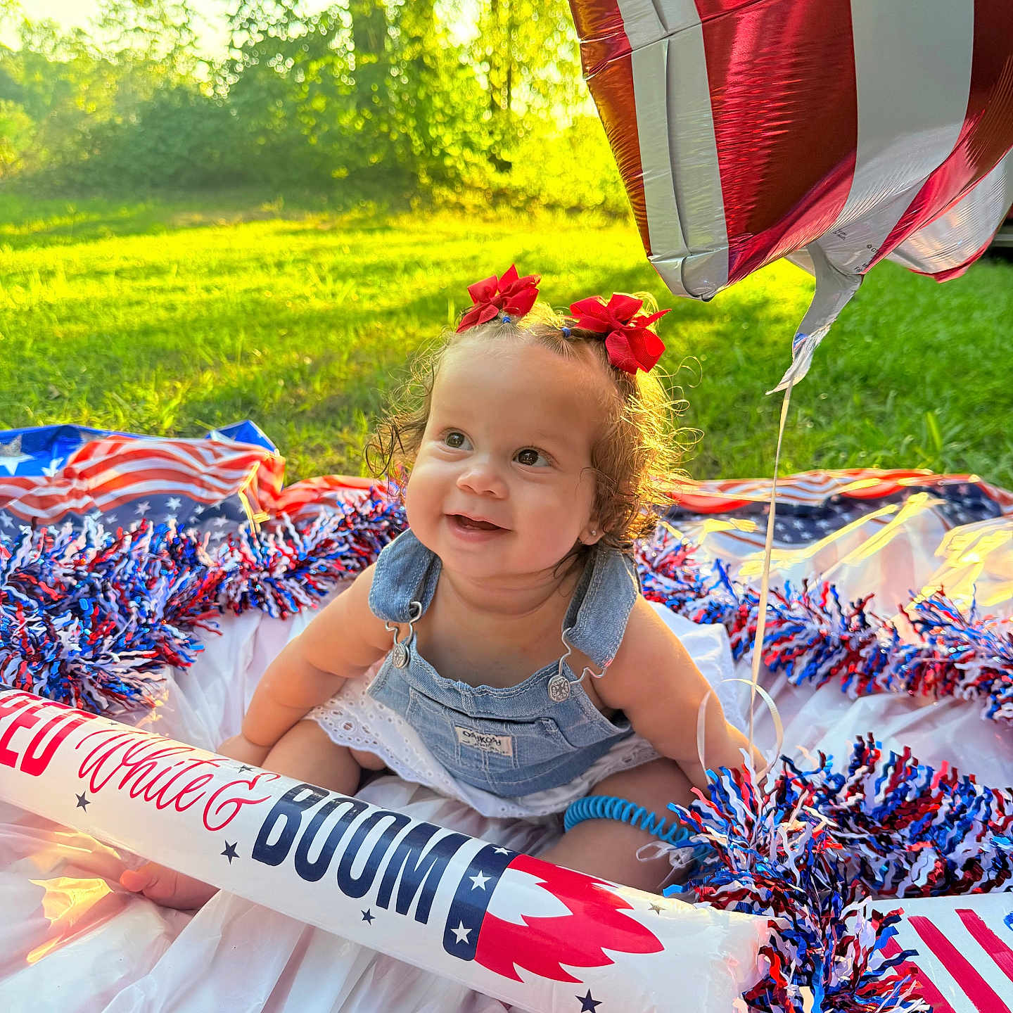 Sanova is registered to the contest to win money with this photo: baby, balloon, celebration, child, cute, decorations, denim_overalls, festive, grass, happy, nature, outdoor, patriotic, pom_poms, portrait, red_bows, sitting, smiling, summer, sunlight