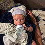 baby, bottle, blanket, cap, couch, feeding, hand, infant, indoors, person, plaid, pattern, resting, striped, toddler, young_child, comfort, care, sleepwear, soft
