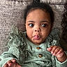 baby, child, tongue_out, green_clothing, ruffles, couch, texture, hand, face, wide_eyes, infant, cute, lying_down, indoors, portrait, cozy, expression, person, closeup, smiling