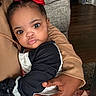 Chloe is registered to the contest to win money with this photo: baby, child, red_bow, black_hair, adult_hand, indoor, curious, pouty_lips, wide_eyes, long_sleeve, holding, couch, brown_skin, cute, portrait, close_up, clothing, fabric, floor, home