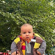 Mehrab is registered to the contest to win money with this photo: baby, child, scarf, outdoor, greenery, tree, person, holding_hands, pout, face, cute, people, daylight, public_place, clothing, hands, expression, casual, photography, urban