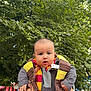 baby, child, scarf, outdoor, greenery, tree, person, holding_hands, pout, face, cute, people, daylight, public_place, clothing, hands, expression, casual, photography, urban