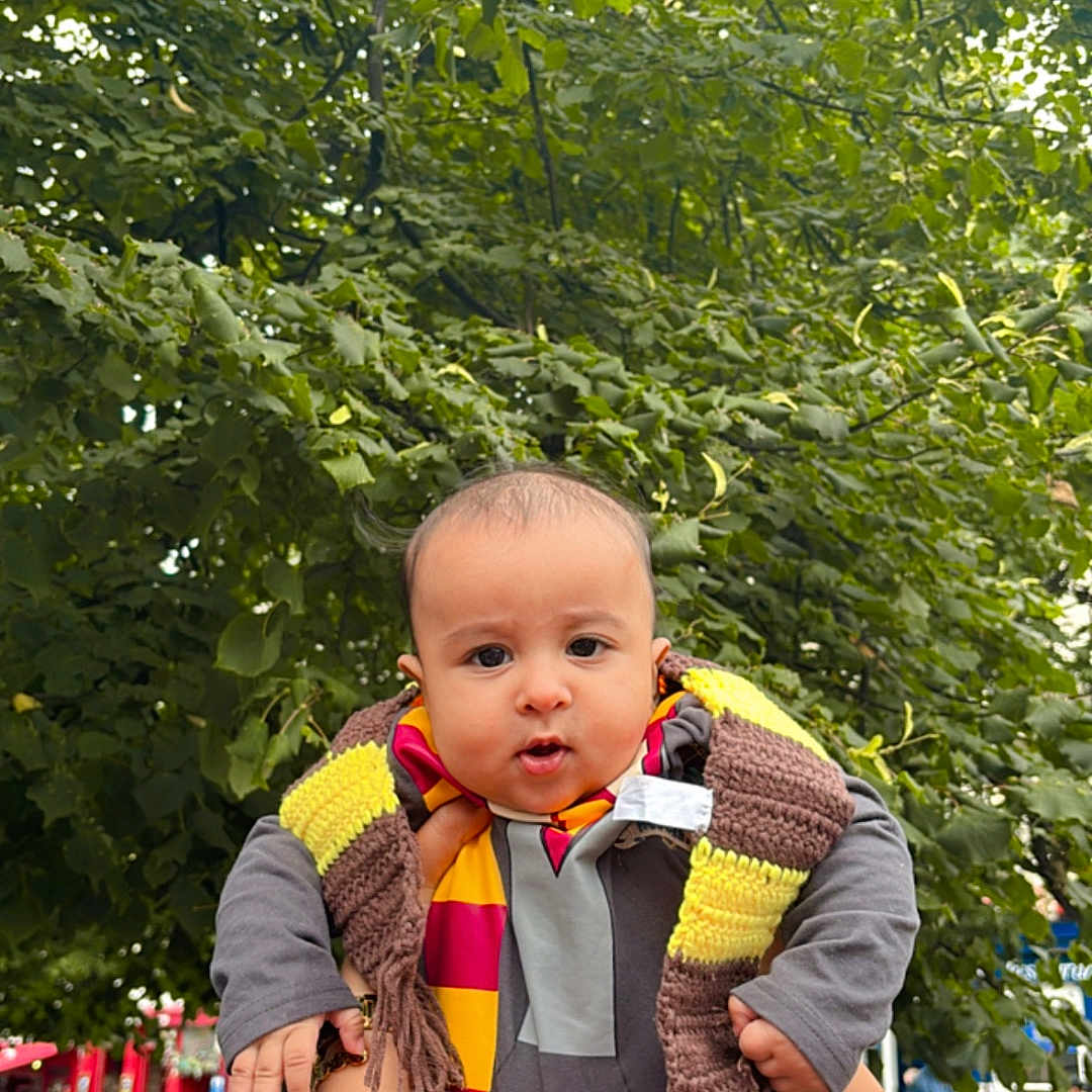 Mehrab is registered to the contest to win money with this photo: baby, casual, child, clothing, cute, daylight, expression, face, greenery, hands, holding_hands, outdoor, people, person, photography, pout, public_place, scarf, tree, urban