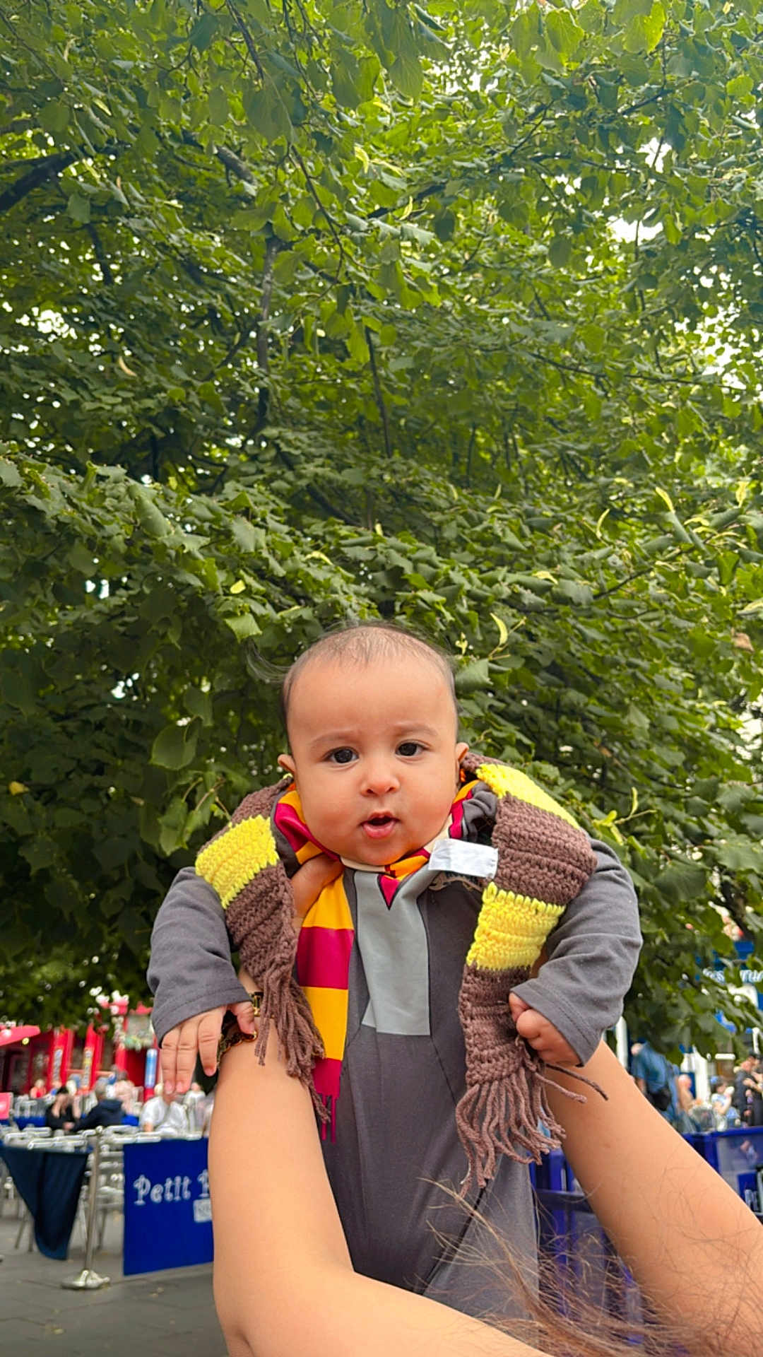 Mehrab is registered to the contest to win money with this photo: baby, child, scarf, outdoor, greenery, tree, person, holding_hands, pout, face, cute, people, daylight, public_place, clothing, hands, expression, casual, photography, urban