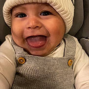 Gael is registered to the contest to win money with this photo: baby, child, smiling, hat, knitted_hat, pom_pom, grey_outfit, knitwear, button, cute, happy, close_up, face, infant, warm_clothing, childhood, person, portrait, indoor, baby_clothes