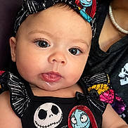 Evelynn is registered to the contest to win money with this photo: baby, child, infant, portrait, close_up, wide_eyes, smiling, gothic, costume, dress, hair_bow, cartoon, skull, skeleton, colorful, black_clothing, adult, indoor, fashion, photography