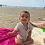 toddler, child, beach, sand, ocean, towel, mat, smile, shirt, diaper, sunny, relaxed, person, legs, water, outdoor, happy, vacation, summer, playtime