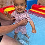 Jules a rejoint le concours — aidez-le/la à gagner de superbes lots ! toddler, child, swimsuit, water, pool, adult_hand, smile, happy, playing, outdoor, bright_colors, red, yellow, blue, legs, person, sitting, chair, summer, fun