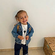 Jade a rejoint le concours — aidez-le/la à gagner de superbes lots ! child, smiling, denim_jacket, jeans, backpack, indoor, wall, floor, shoes, person, happy, toddler, casual_clothing, standing, young_child, portrait, cute, fashion, footwear, tile_floor