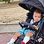 toddler, child, stroller, outdoor, park, trees, grass, sidewalk, clothing, socks, expression, face, seatbelt, summer, playground, person, baby, casual, sunlight, nature