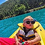 Ethan participe au concours pour gagner de l'argent avec cette photo : baby, sunglasses, life_jacket, kayak, water_bottle, lake, forest, water, outdoor, sunny, child, nature, summer, adventure, person, recreation, greenery, sky, trees, vacation