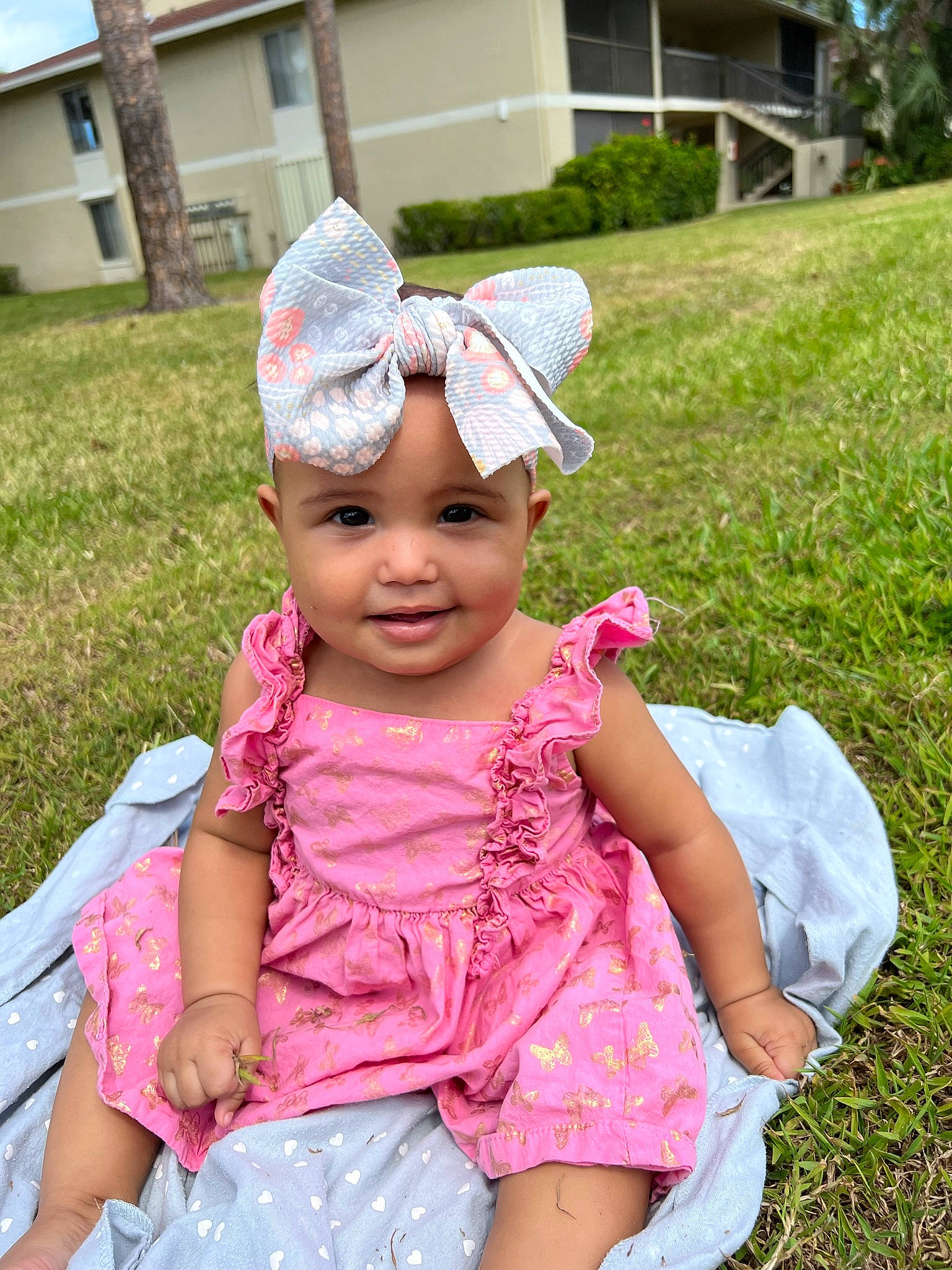 Kalani is registered to the contest to win money with this photo: baby, baby_toddler_clothing, cap, child, event, eyewear, fashion_accessory, fun, grass, happy, headwear, joy, leisure, magenta, person, pink, plant, recreation, sitting, summer