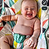 Enzo is registered to the contest to win money with this photo: baby, infant, child, smiling, laughing, portrait, sitting, bouncer, baby_seat, colorful, geometric_pattern, indoor, playful, happy, bare_chested, diaper, feet, hands, furniture, photograph
