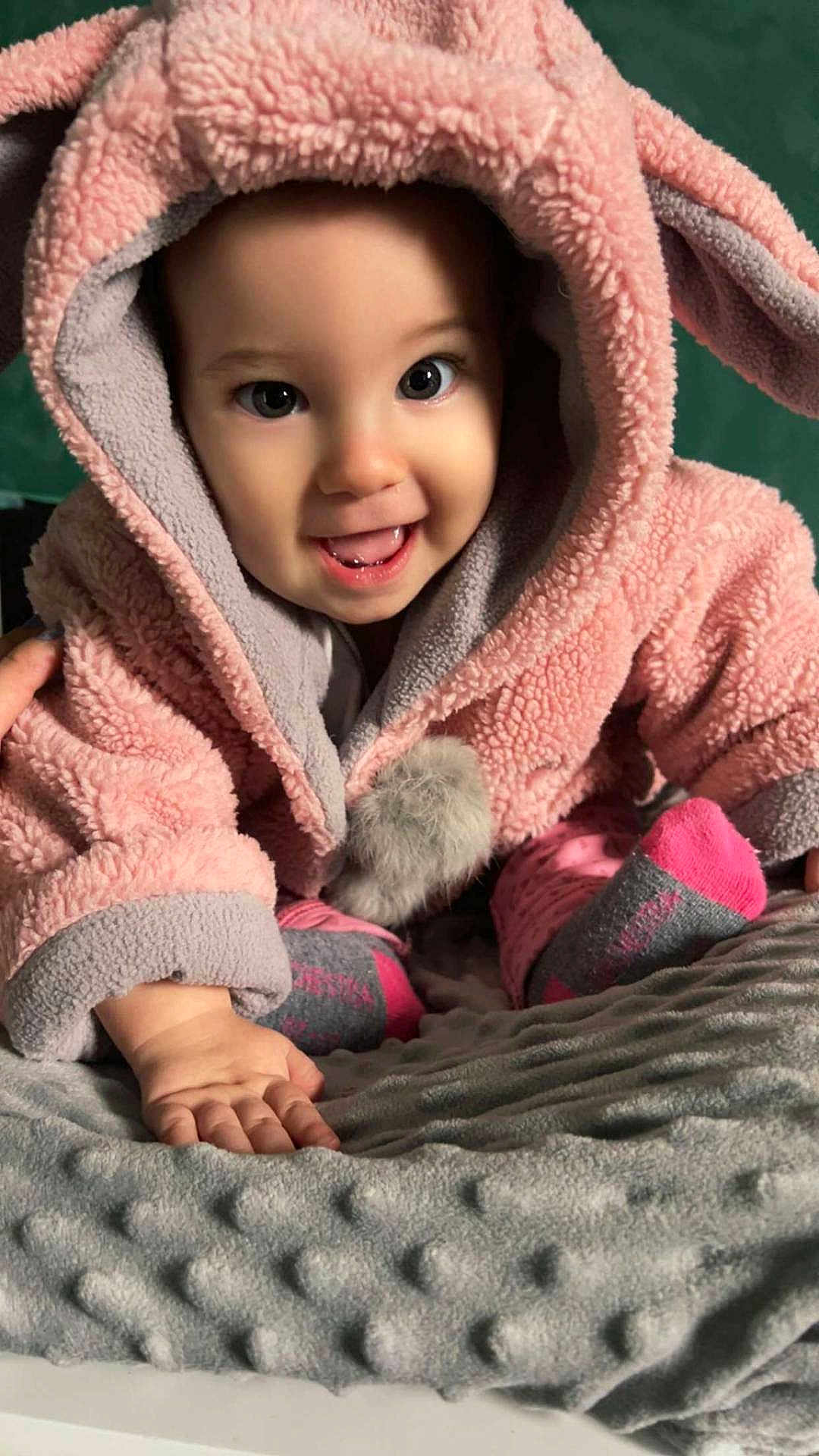 Lyanna participe au concours pour gagner de l'argent avec cette photo : baby, child, pink_hood, bunny_ears, smiling, crawling, blanket, soft_texture, cute, happy, indoors, face, hand, sock, gray_blanket, cozy, warm_clothing, infant, portrait, closeup