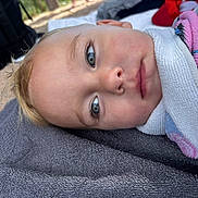Liam participe au concours pour gagner de l'argent avec cette photo : child, baby, face, blue_eyes, blond_hair, towel, blanket, outdoor, portrait, close_up, skin, expression, lying_down, soft_light, young, person, head, cute, resting, daylight