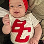 Sophia is registered to the contest to win money with this photo: accessories, baby, cap, clothing, costume, couch, cushion, face, furniture, happy, hat, head, homedecor, pants, person, photography, portrait, shirt, t_shirt, text