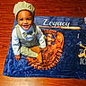 Legacy is registered to the contest to win money with this photo: toddler, child, smiling, milestone_blanket, vintage_clothing, cap, bow_tie, suspenders, brown_shoes, wooden_floor, indoor, portrait, baby, sitting, happy, person, flooring, cute, infant, playtime