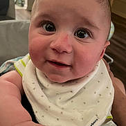 Calvin joined the competition — help win amazing prizes! baby, infant, face, eyes, hand, bib, clothing, indoor, person, portrait, cute, expression, skin, head, smile, holding, young_child, warm_lighting, background_blur, closeup