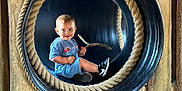 Morgan joined the competition — help win amazing prizes! toddler, child, smile, blue_clothing, stick, black_tube, rope, wooden_fence, wood_chips, outdoor, playground, sneakers, happy, play, person, daylight, nature, fun, circular_frame, casual