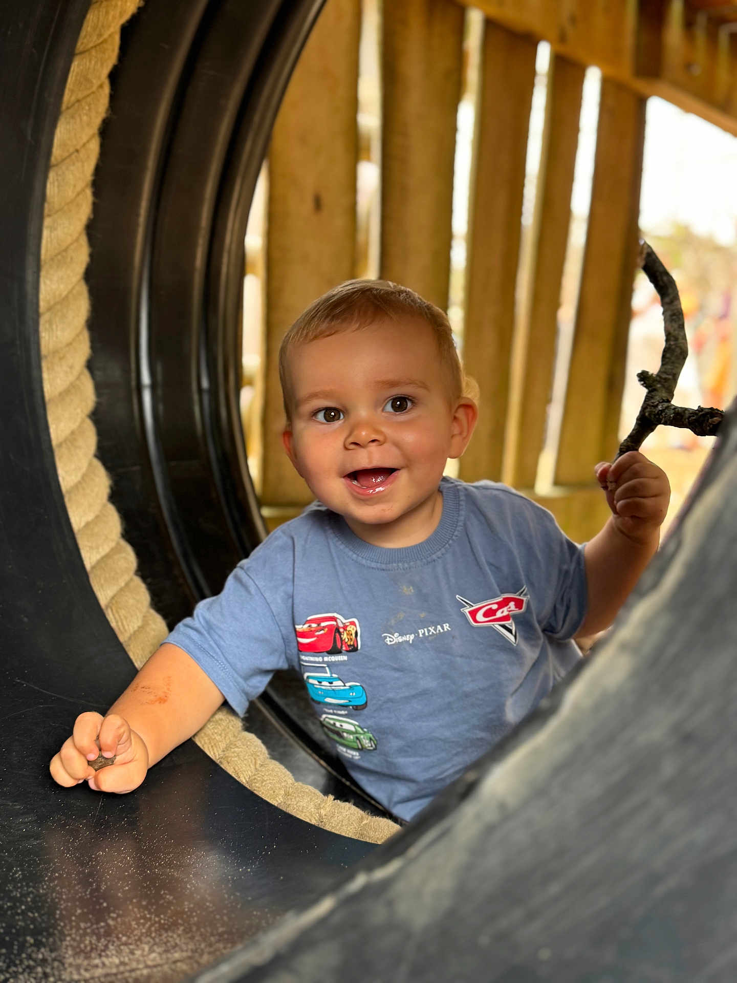 Morgan is registered to the contest to win money with this photo: child, toddler, smiling, playground, tunnel, stick, blue_shirt, Disney, Pixar, Cars, outdoor, play, happy, cute, face, person, toy, wood, rope, adventure