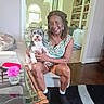 Dillon J Mason joined the competition — help win amazing prizes! woman, dog, indoor, sitting, smiling, glass_table, flower, home, furniture, bookshelf, wood_floor, casual_clothing, portrait, pet, companion, living_room, decor, happy, human, animal