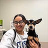Boog joined the competition — help win amazing prizes! woman, dog, glasses, indoor, smile, pet, casual_clothing, holding, short_hair, light_skin, black_dog, small_dog, ears, face, person, portrait, sweatshirt, friendly, happy, room