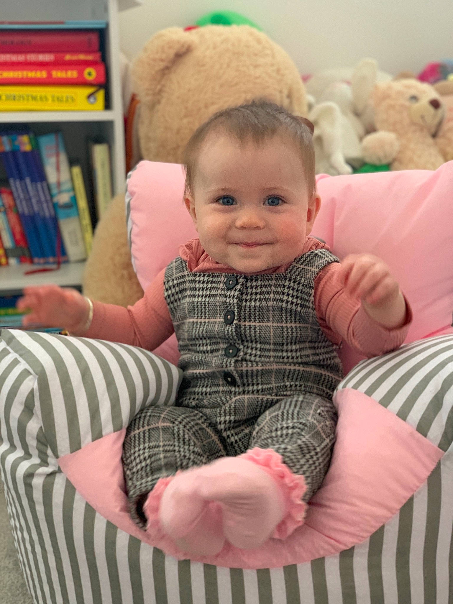 Olivia Rose is registered to the contest to win money with this photo: baby, baby_products, baby_toddler_clothing, book, bookcase, child, comfort, human, human_body, joy, linens, nose, person, plush, publication, shelf, shelving, sitting, stuffed_toy, textile