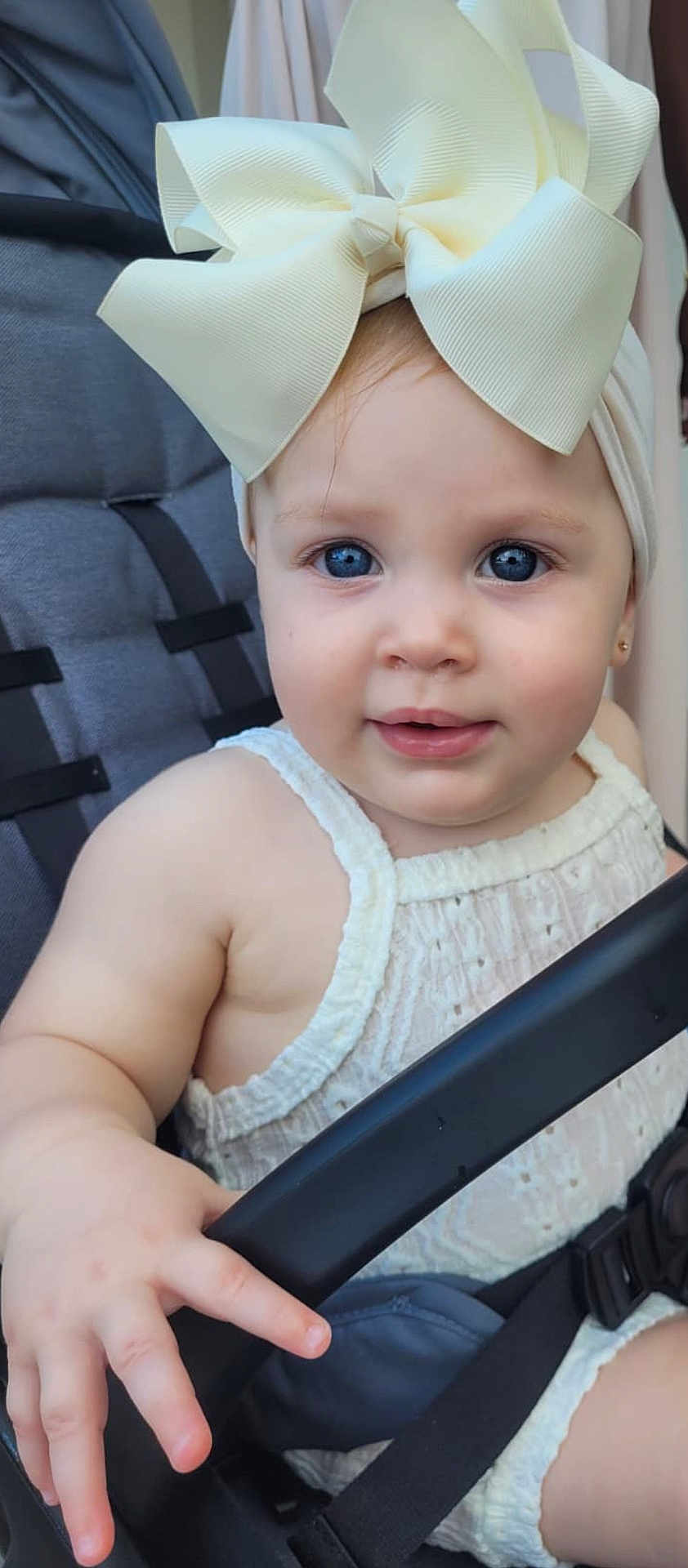 Valentina joined the competition — help win amazing prizes! baby, child, blue_eyes, bow, headwear, stroller, safety_bar, white_clothing, cute, infant, hand, face, portrait, outdoor, seatbelt, skin, expression, baby_fashion, close_up, adorable