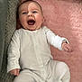 baby, infant, smiling, laughing, onesie, white_clothing, pink_blanket, soft_texture, cushion, cozy, happy, child, face, mouth_open, indoor, cute, young, person, lying_down, joyful