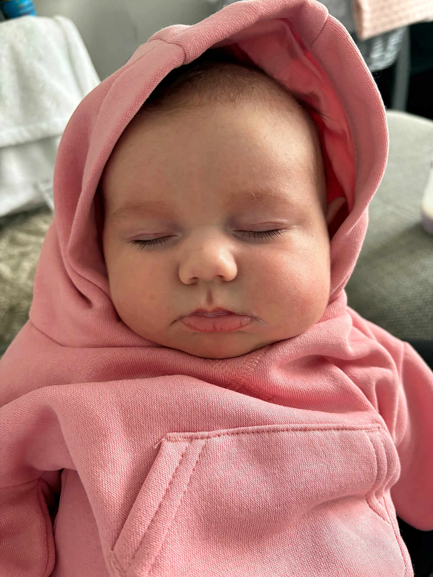 Anna is registered to the contest to win money with this photo: baby, sleeping, hoodie, pink_clothing, face, infant, child, cheeks, closeup, peaceful, rest, soft_light, indoors, portrait, cute, cozy, apparel, headwear, clothing, young_child