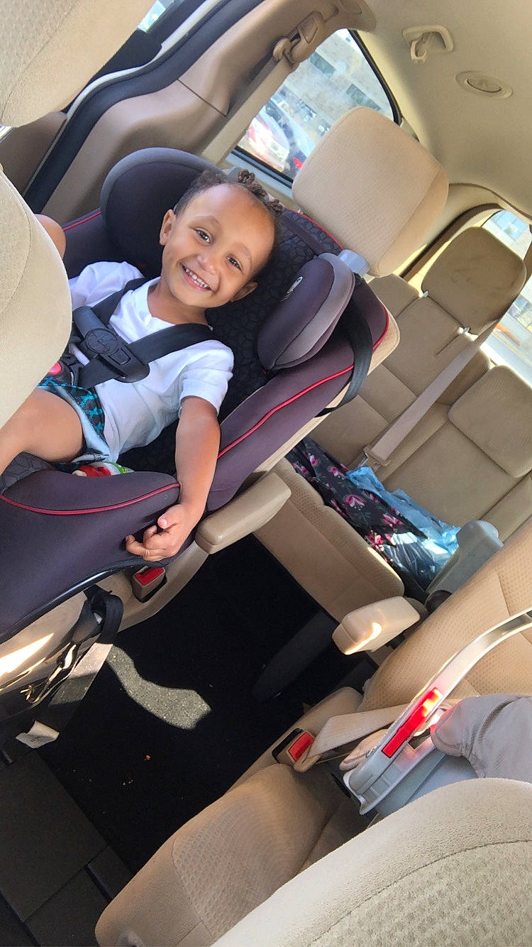 Milo is registered to the contest to win money with this photo: auto_part, automotive_design, car_seat, car_seat_cover, comfort, head_restraint, joy, knee, leg, mode_of_transport, motor_vehicle, person, personal_luxury_car, seat_belt, smile, sneakers, steering_part, steering_wheel, toddler, vehicle