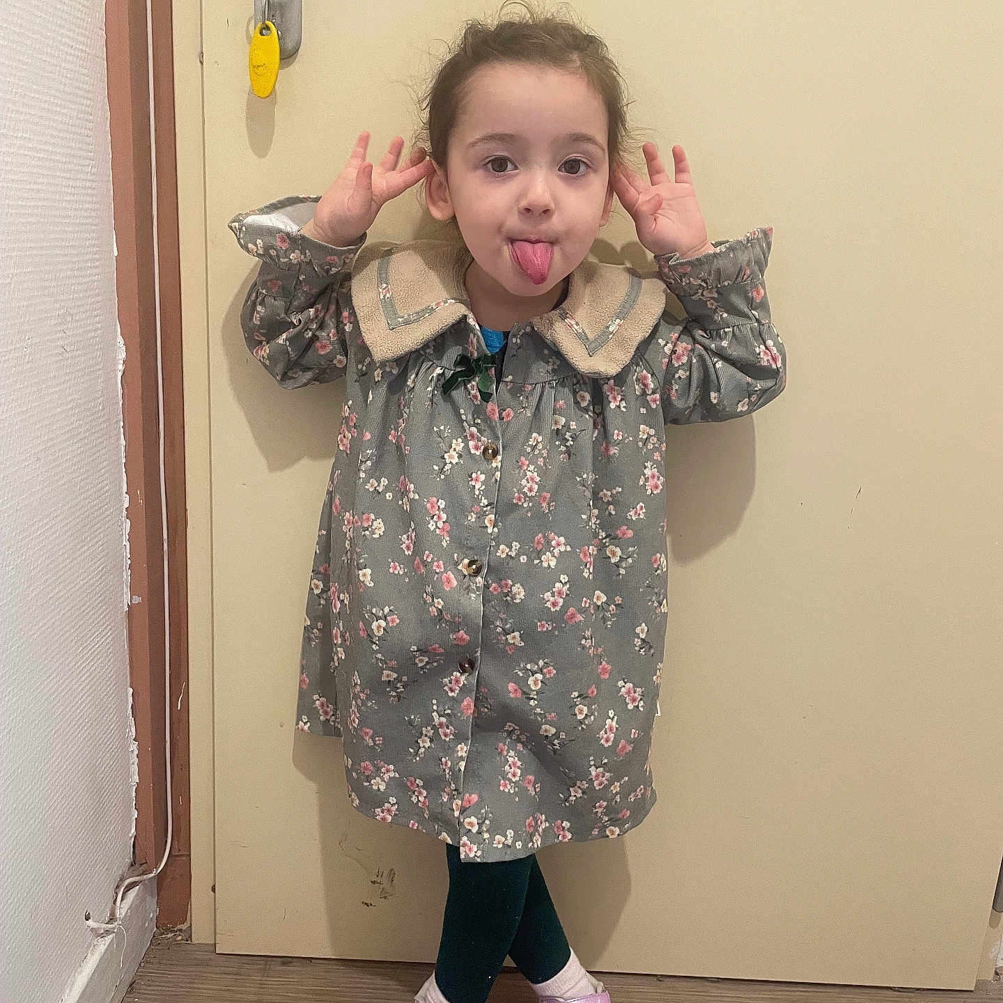 Naïma a rejoint le concours — aidez-le/la à gagner de superbes lots ! casual, child, cute, door, expression, floor, floral_coat, funny_face, girl, hands_up, indoor, leggings, mischievous, person, pink_shoes, playful, standing, tongue_out, wall, young