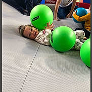 Naïma a rejoint le concours — aidez-le/la à gagner de superbes lots ! child, cute, exercise_ball, floor, green_ball, group, hand, happy, indoor, infant, lying_down, pajamas, patterned_pants, person, play, play_mat, recreation, smiling, toddler, toy