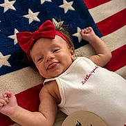 Michelle joined the competition — help win amazing prizes! american_flag, baby, blanket, celebration, child, cute, happy, headband, holiday, infant, lying_down, onesie, patriotic, portrait, red_bow, red_white_blue, sign, smiling, tongue_out, young_child