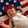 baby, infant, red_bow, onesie, american_flag, blanket, patriotic, smiling, tongue_out, cute, celebration, holiday, child, happy, headband, lying_down, sign, red_white_blue, young_child, portrait