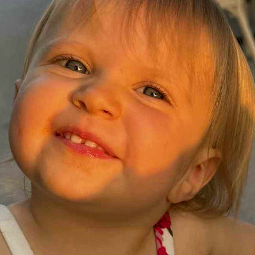 Lylia a rejoint le concours — aidez-le/la à gagner de superbes lots ! baby, blond_hair, casual_clothing, cheeks, child, closeup, cute, daylight, expression, face, happy, head_and_shoulders, indoor, person, portrait, smiling, sunlight, toddler, warm_light, young_child