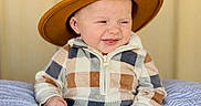 Colsen is registered to the contest to win money with this photo: baby, child, clothing, cozy, cute, expression, footwear, happy, hat, indoor, infant, onesie, pillow, plaid, portrait, seated, smile, soft, warm, wearing