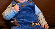 Colsen is registered to the contest to win money with this photo: baby, child, smiling, blue_overalls, brown_couch, thumbs_up, happy, infant, cute, portrait, indoor, clothing, footwear, sitting, face, person, cozy, quilted, young_child, expression