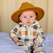Colsen joined the competition — help win amazing prizes! baby, child, hat, checkered_outfit, sitting, cushion, striped_cushion, indoor, portrait, cute, cozy, infant, fashion, blue_eyes, soft_lighting, neutral_background, hands_clenched, footwear, warm_colors, young_child