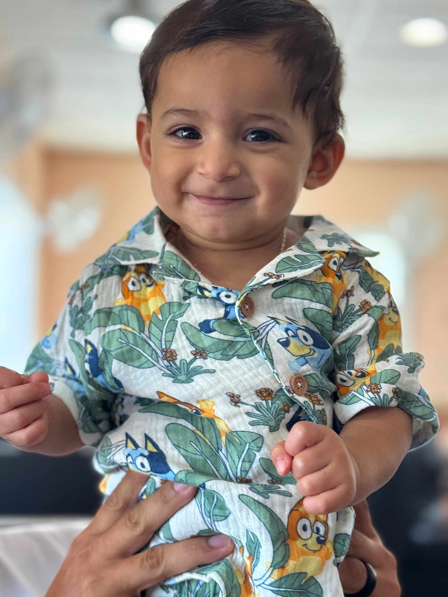 Enzo joined the competition — help win amazing prizes! toddler, child, smile, face, hand, shirt, patterned_clothing, indoor, person, baby, portrait, cute, happy, holding, adult_hand, colorful, cartoon, green, orange, background_blur