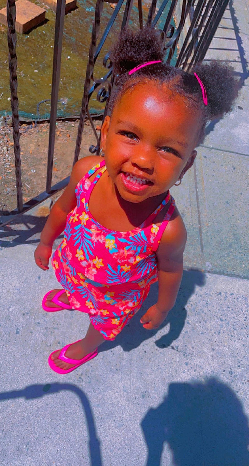 Miangel is registered to the contest to win money with this photo: baby_toddler_clothing, child, city, fence, fun, hairstyle, happy, head, jewellery, leisure, magenta, necklace, person, pink, play, recreation, sandal, sitting, smile, toddler