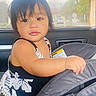 baby, black_hair, car_interior, car_seat, child, cute, daylight, expression, face, floral_dress, hand, indoors, looking_away, person, portrait, seatbelt, sitting, toddler, window, young_child