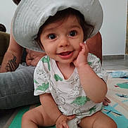 Joseph participe au concours pour gagner de l'argent avec cette photo : baby, child, hat, smile, dinosaur_print, tshirt, play_mat, indoor, adult, glasses, tattoo, happy, sitting, hand_on_face, floor, person, cute, family, joyful, portrait