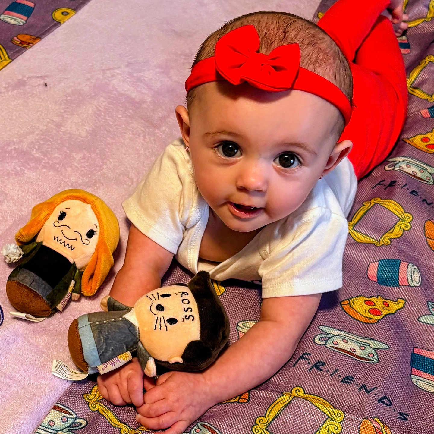 Grey is registered to the contest to win money with this photo: baby, blanket, child, colorful, crawling, cute, friends_theme, happy, indoors, infant, lying_down, playtime, plush_toy, portrait, red_headband, red_pants, smiling, soft_toys, white_shirt, young_child